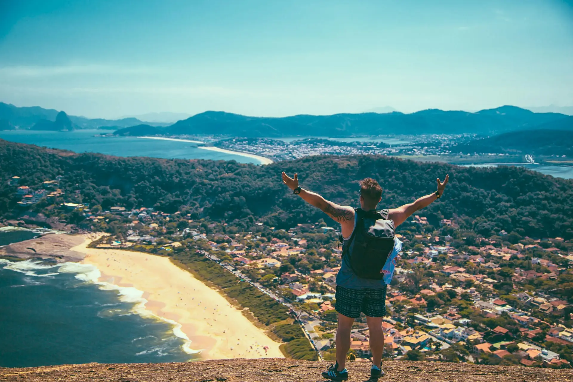 Traveller overlooking a scenic coastal town from a mountain top.