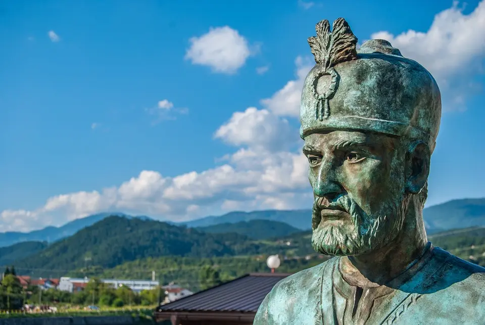 Bronze statue of an Ottoman figure with mountains in the background in Bosnia.